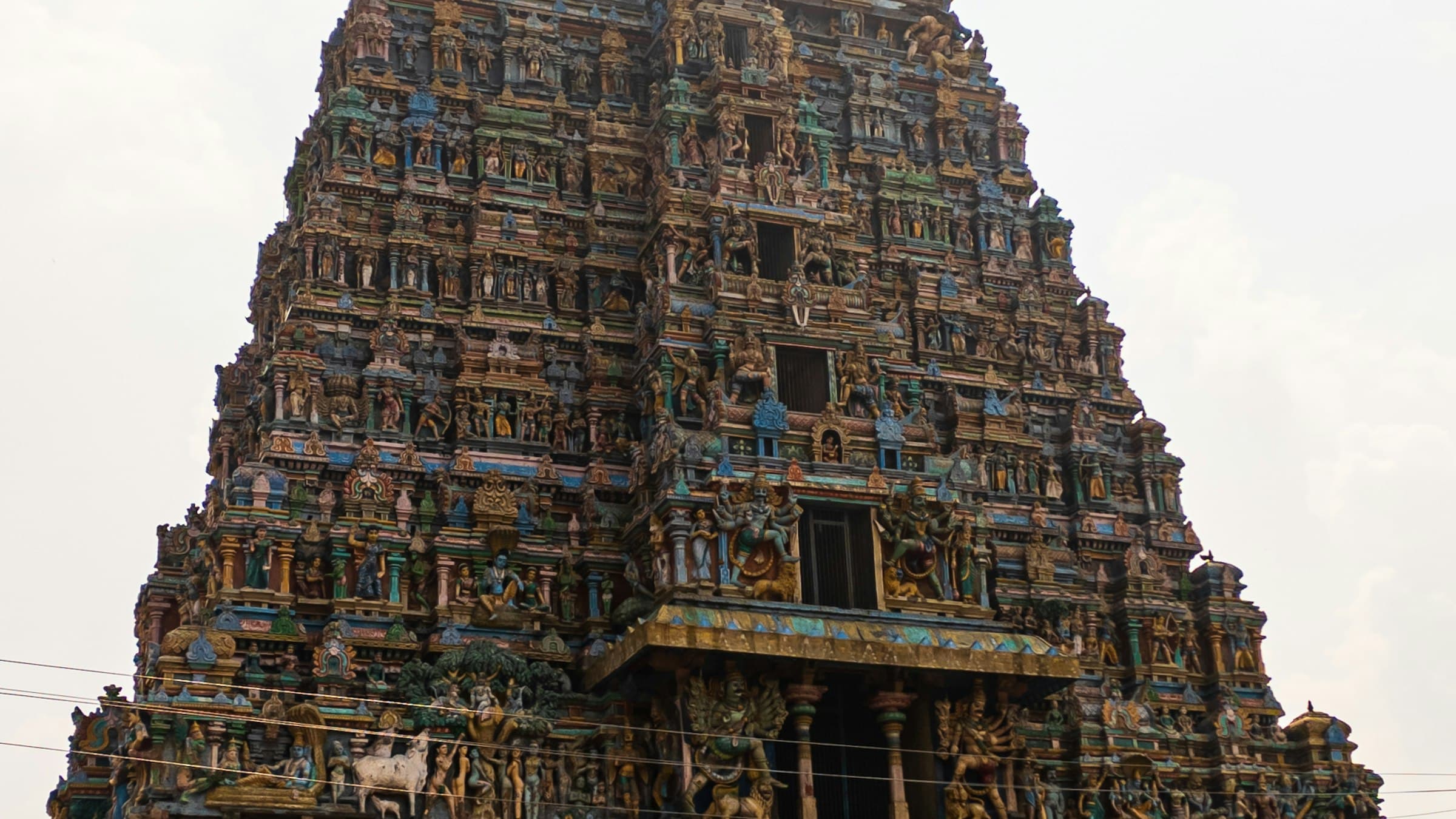Towering painted gopuram of a Dravidian temple in Madurai, Tamil Nadu, covered in carved figures