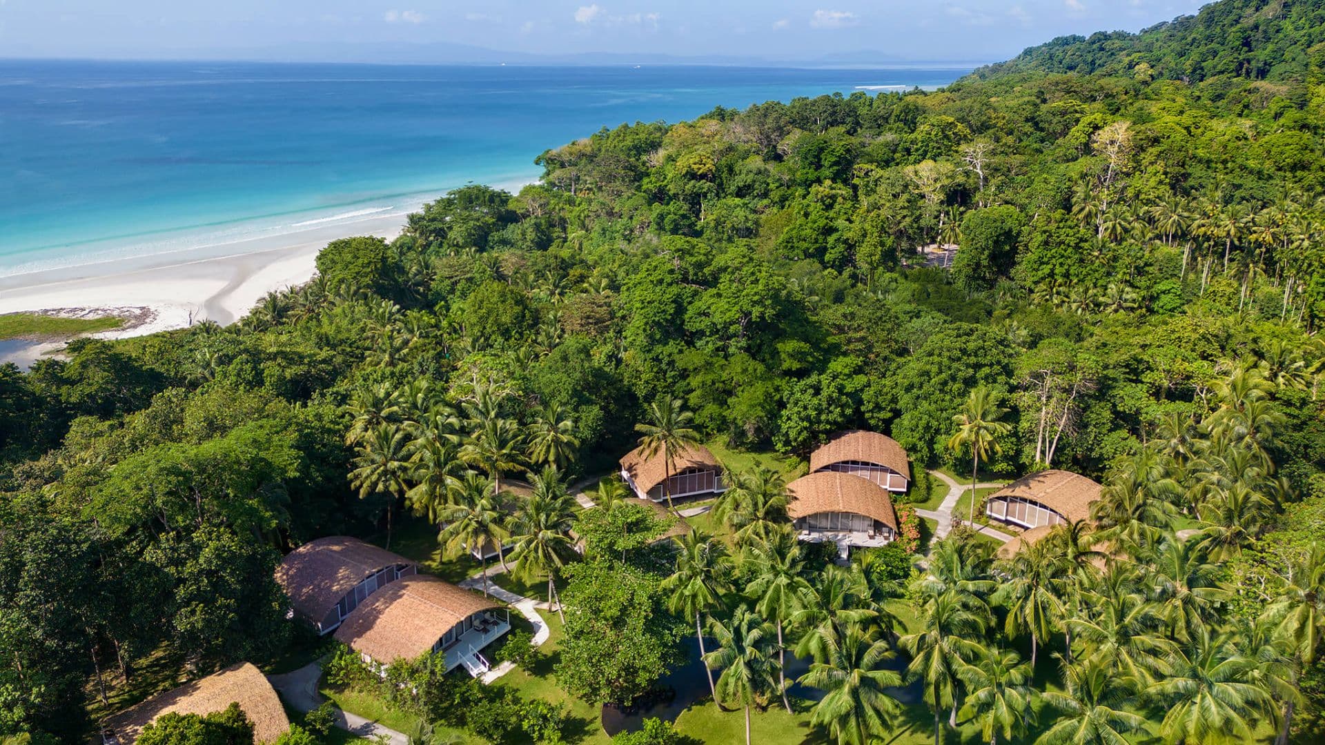 Aerial view of Taj Exotica Resort & Spa, Andamans, showing villas set among forest canopy beside the beach