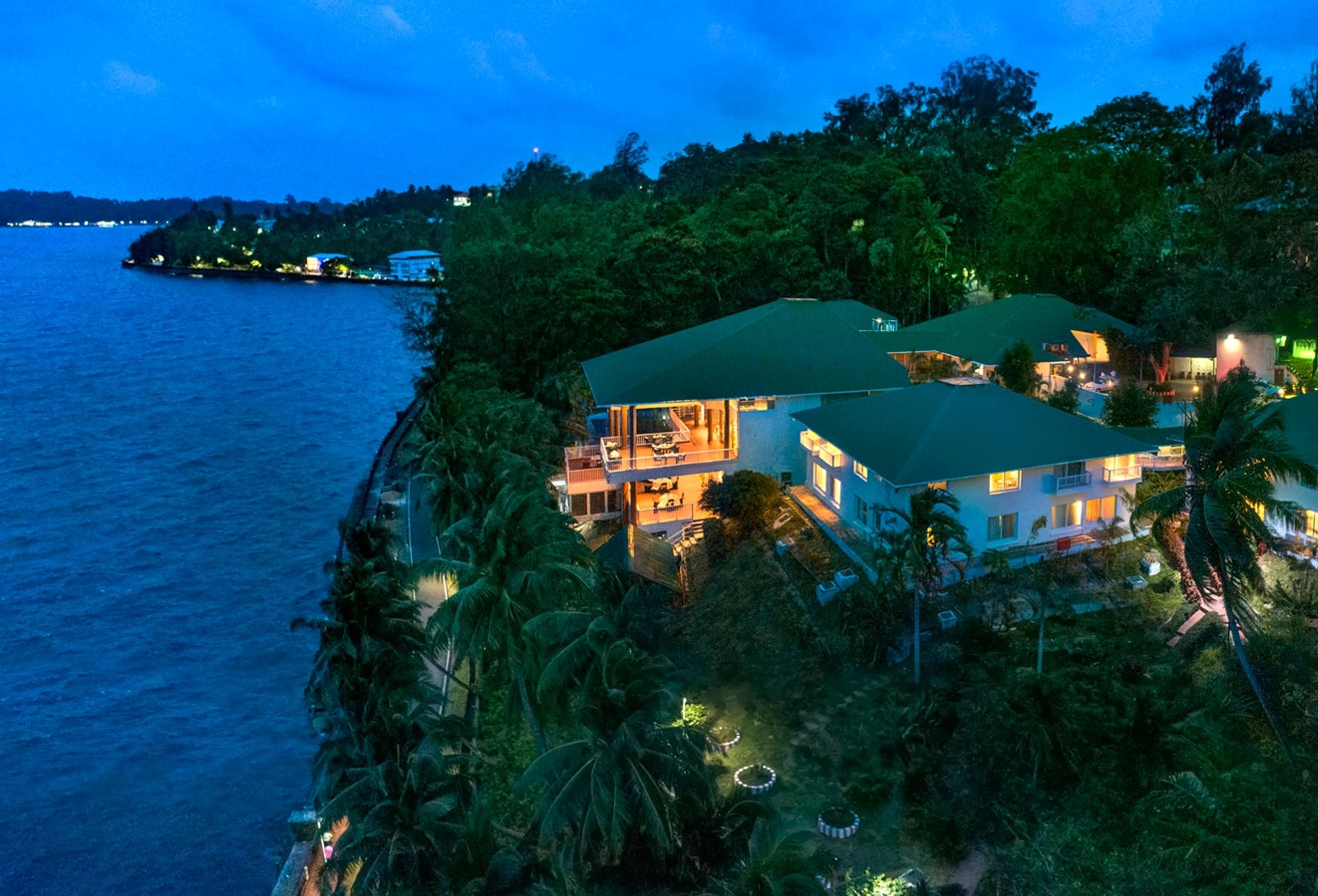 Aerial dusk view of Welcomhotel Bay Island's timber-roofed pavilions on Marine Hill overlooking Port Blair harbour