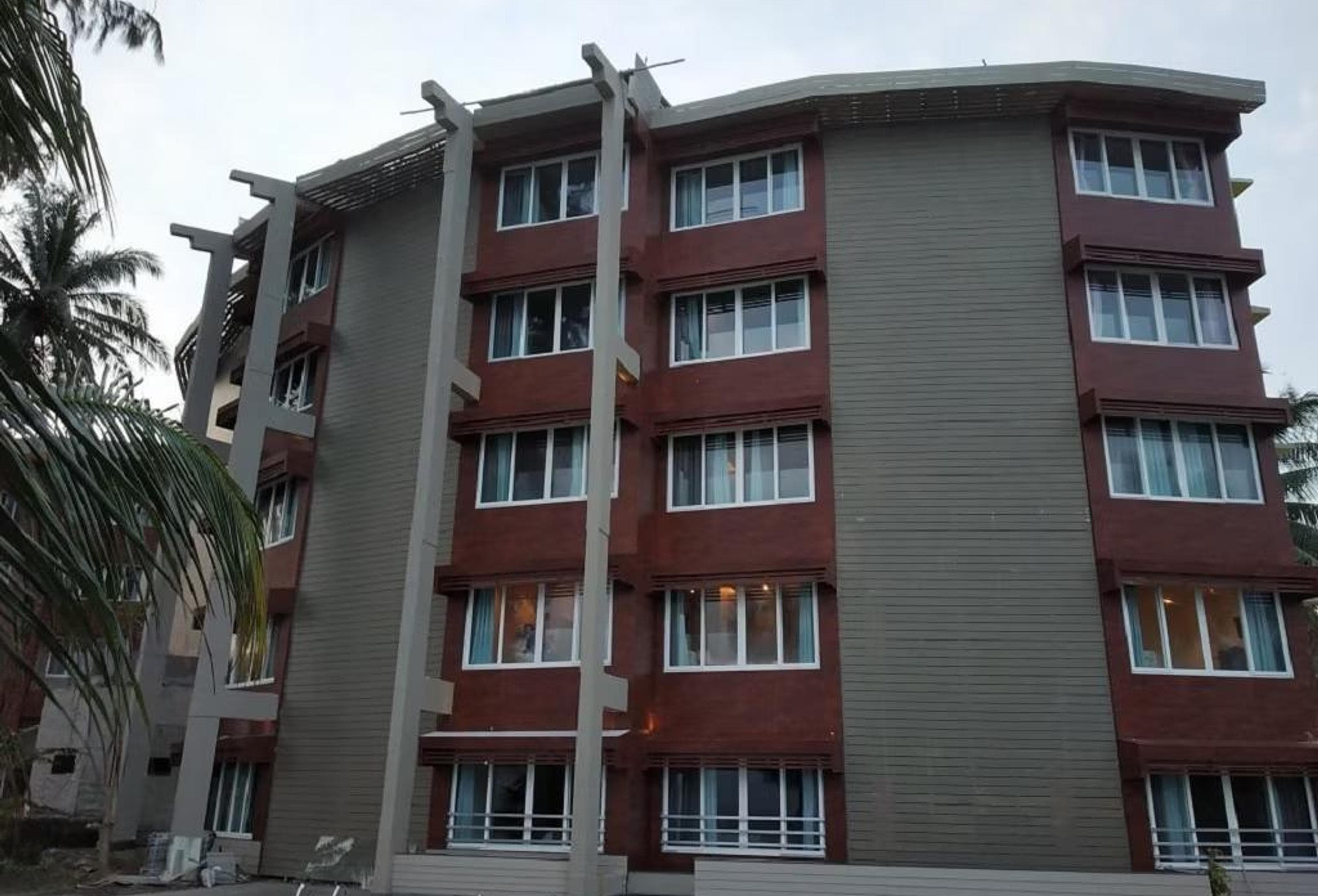 Exterior of Sinclairs Bayview Port Blair, a multi-storey hotel building framed by palm trees