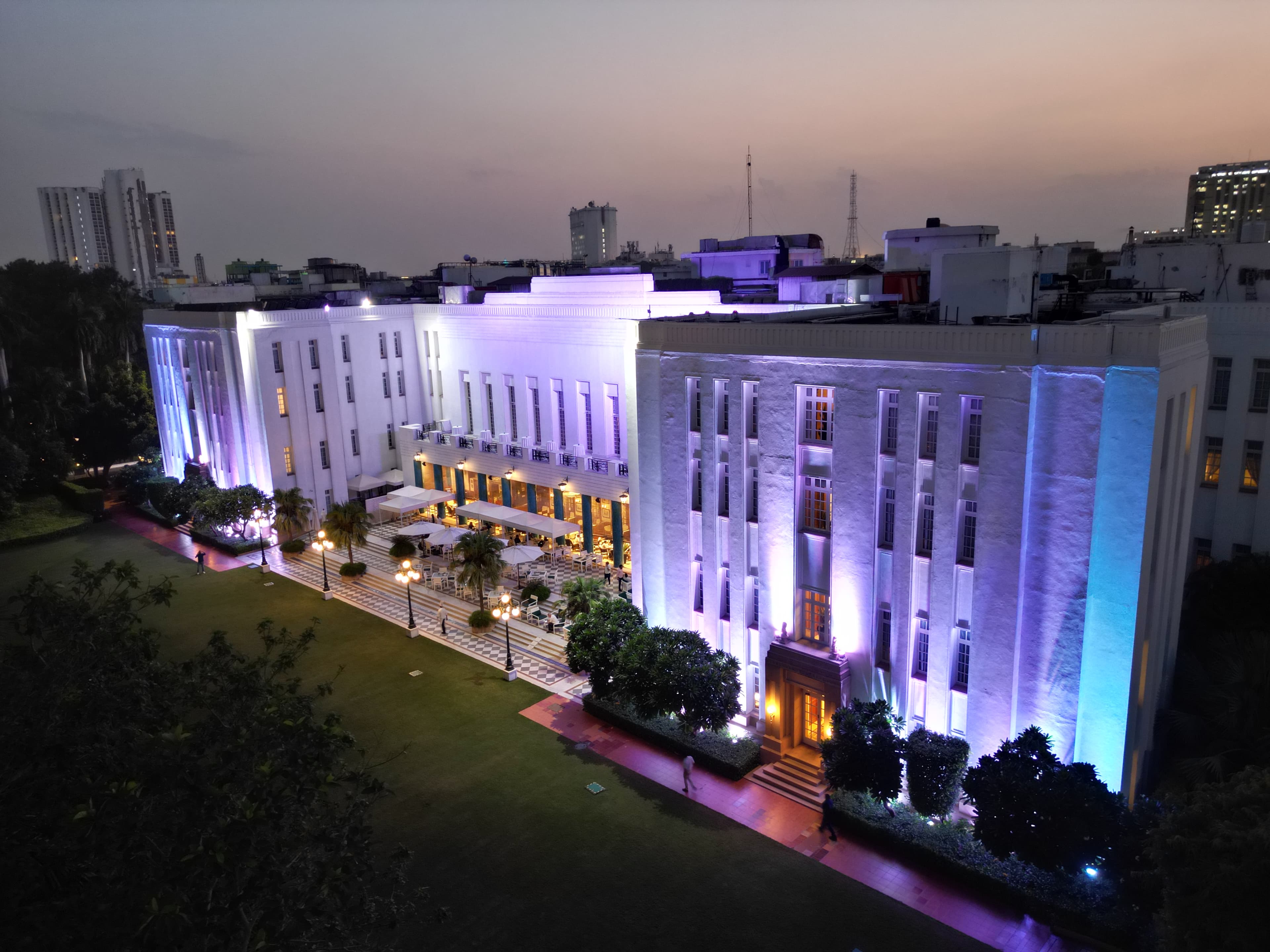 The Imperial New Delhi's colonial-era facade lit up at night, viewed across its front driveway