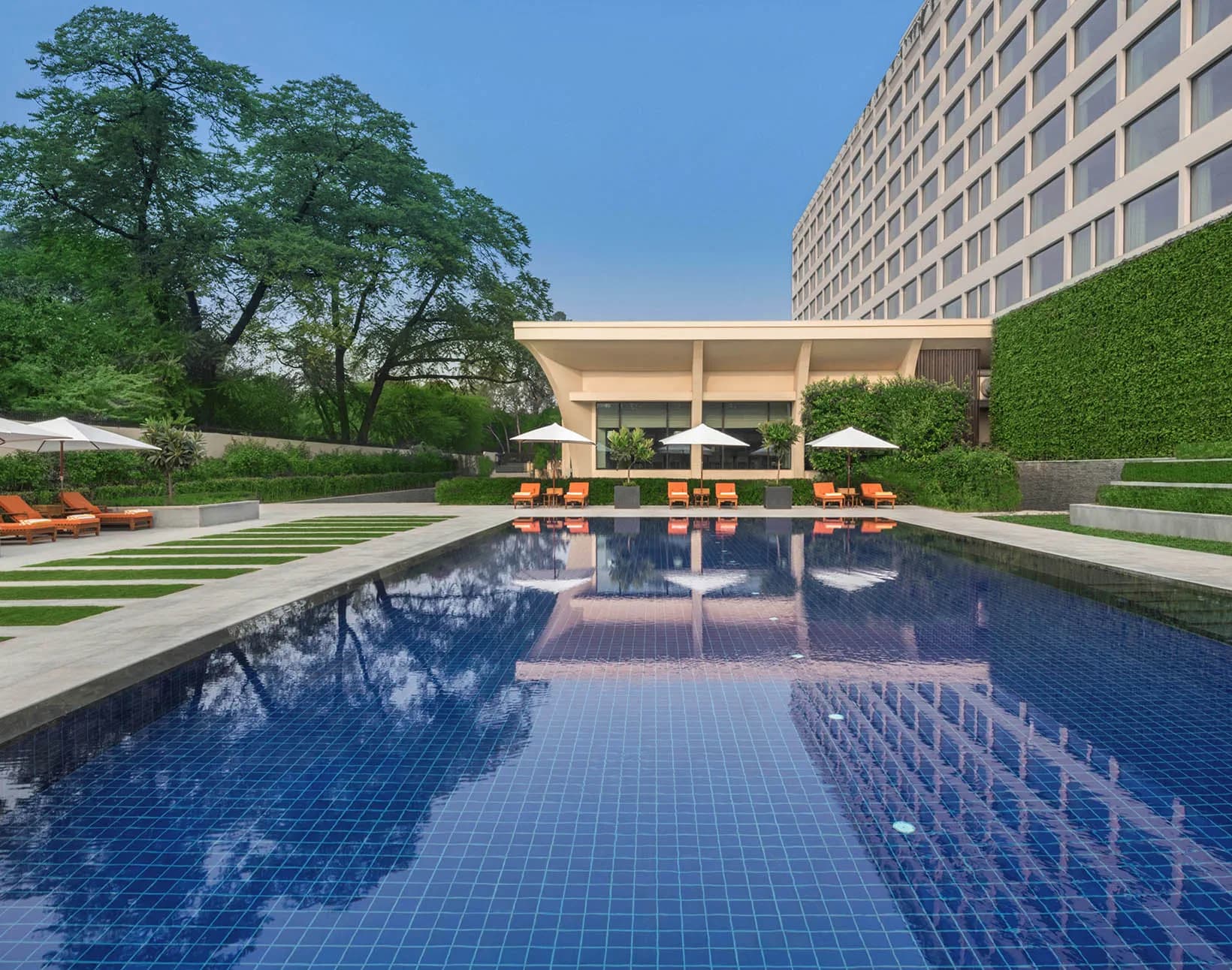 The Oberoi New Delhi's outdoor swimming pool framed by sculpture and manicured gardens