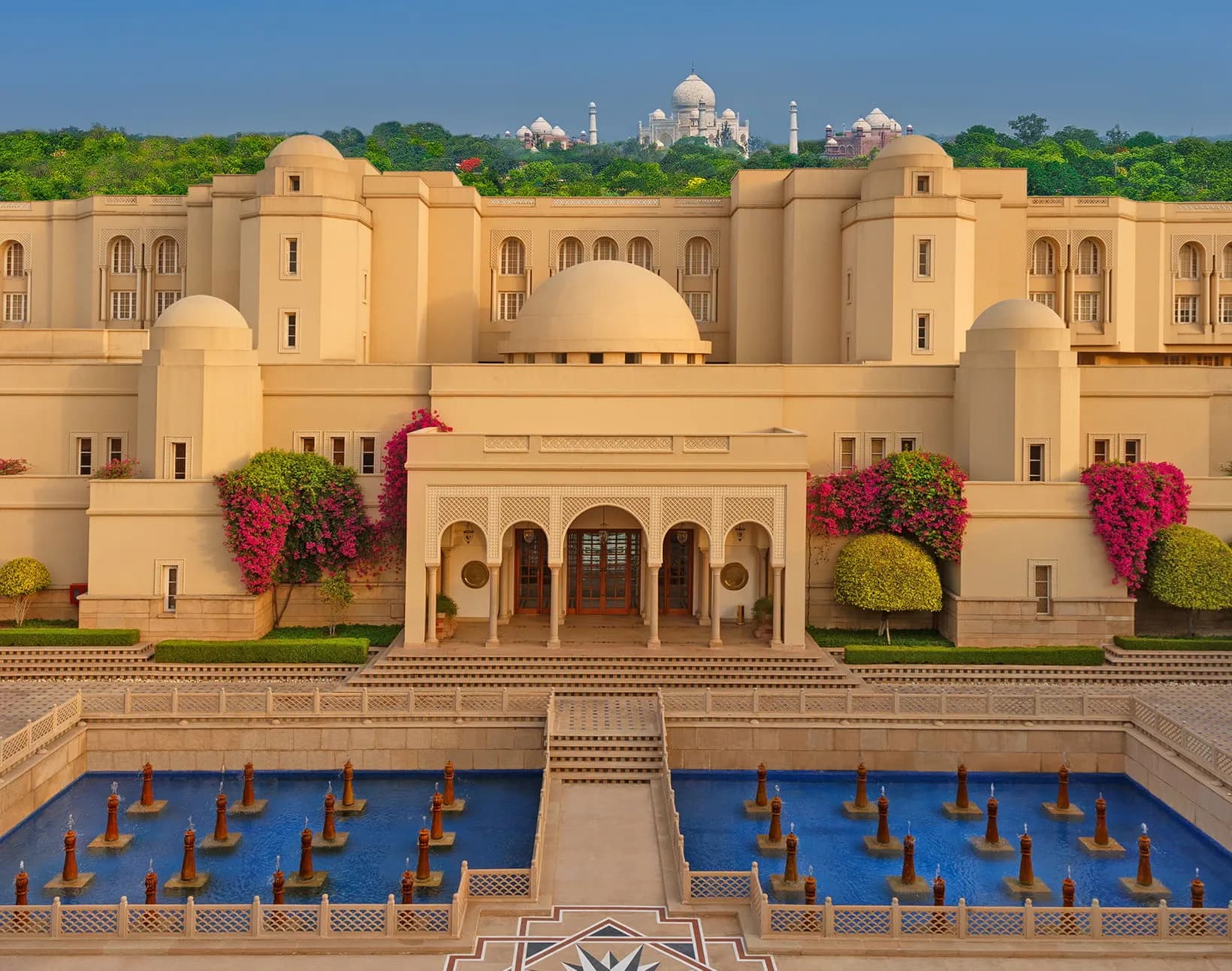 The Oberoi Amarvilas facade with the Taj Mahal visible on the skyline behind the hotel