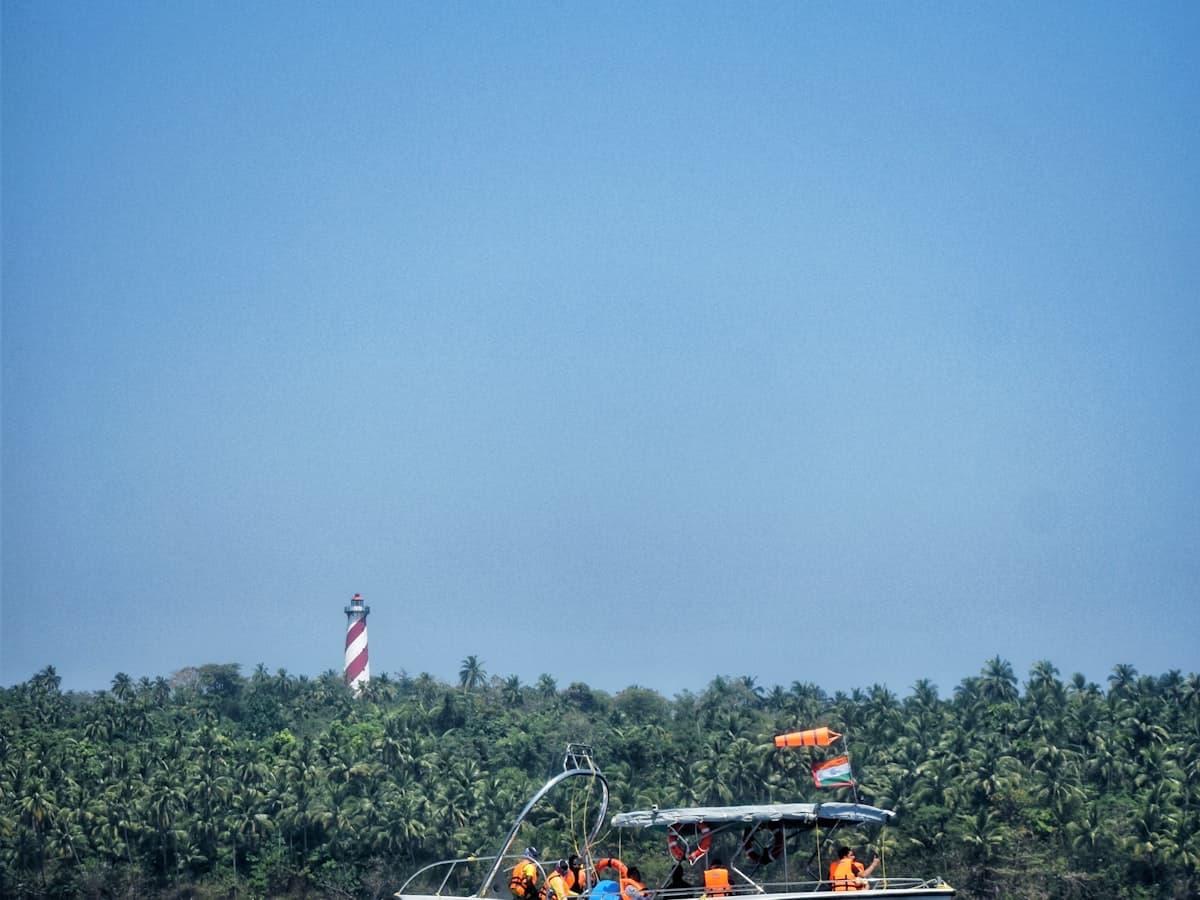 A passenger ferry departing Port Blair with a lighthouse and coastline behind