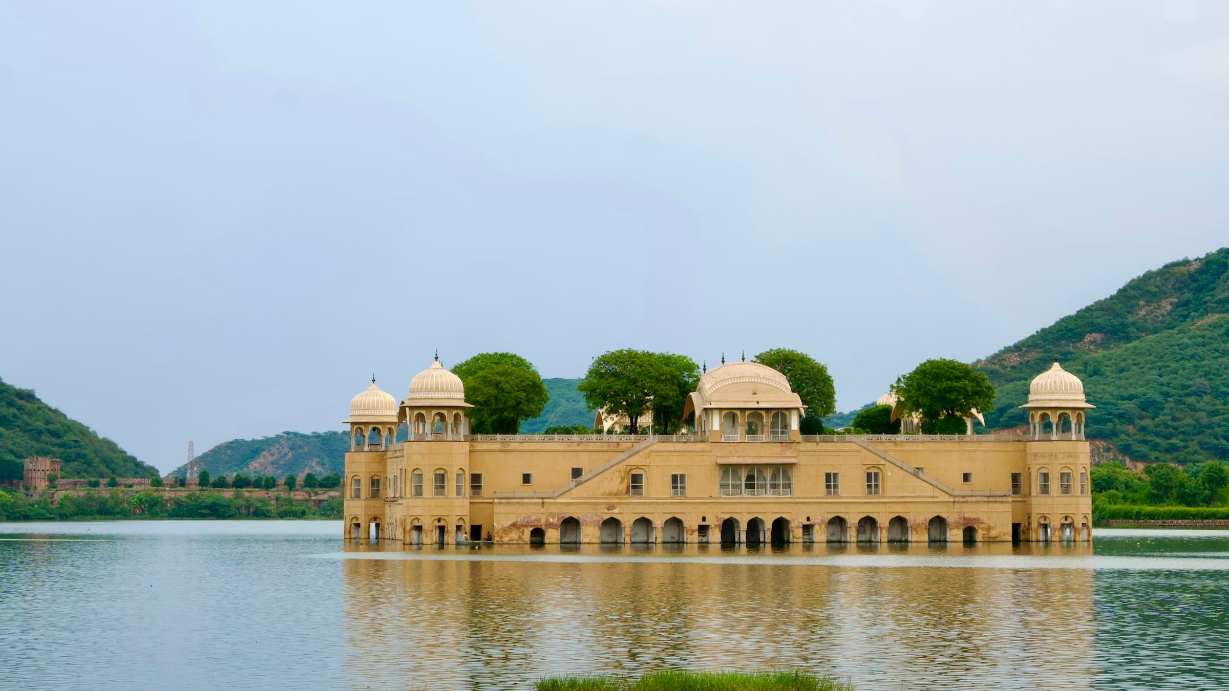 Jal Mahal Palace rising from the center of Man Sagar Lake in Jaipur, surrounded by water and distant hills