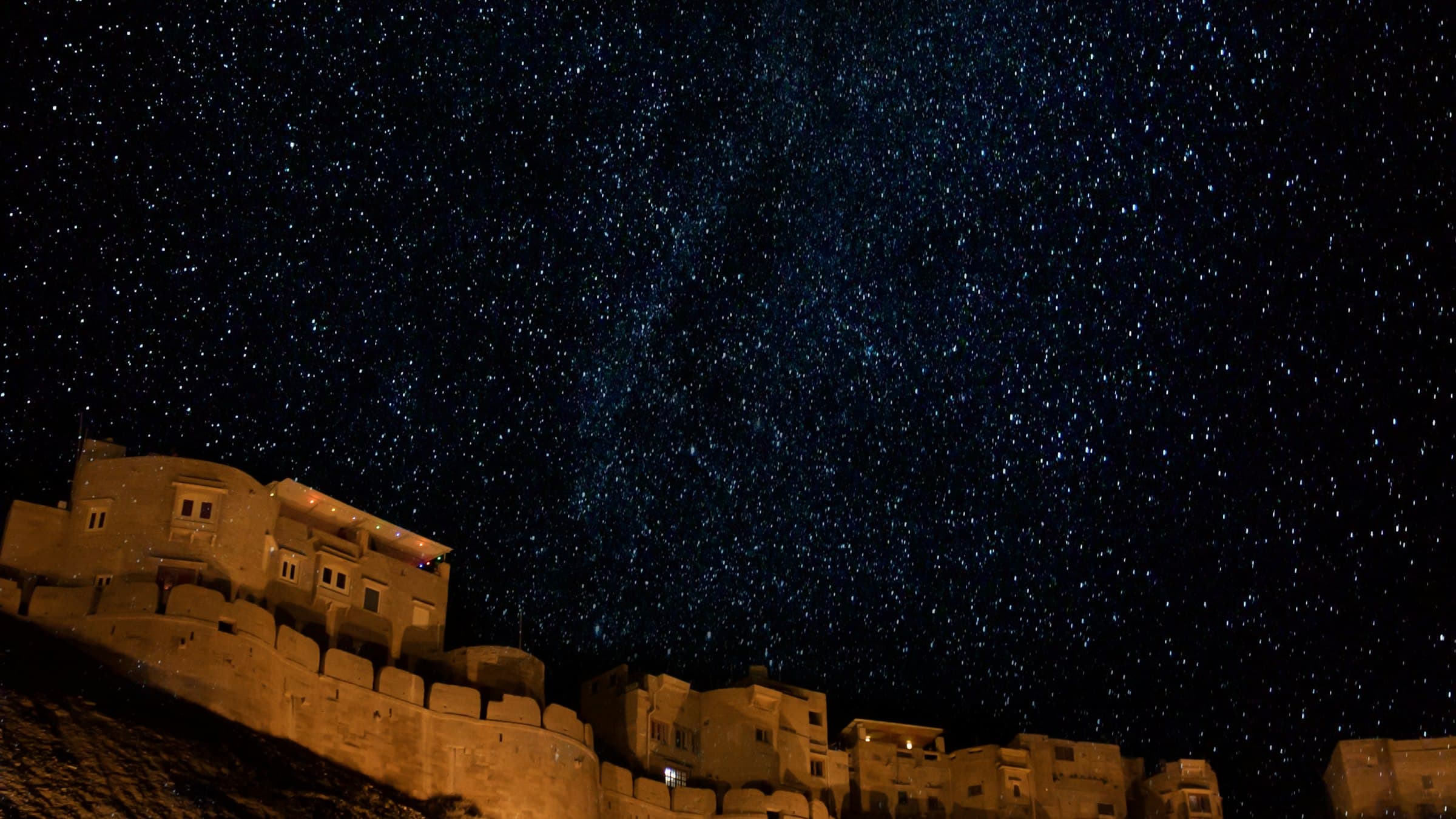 Jaisalmer Fort's illuminated ramparts beneath a star-filled night sky
