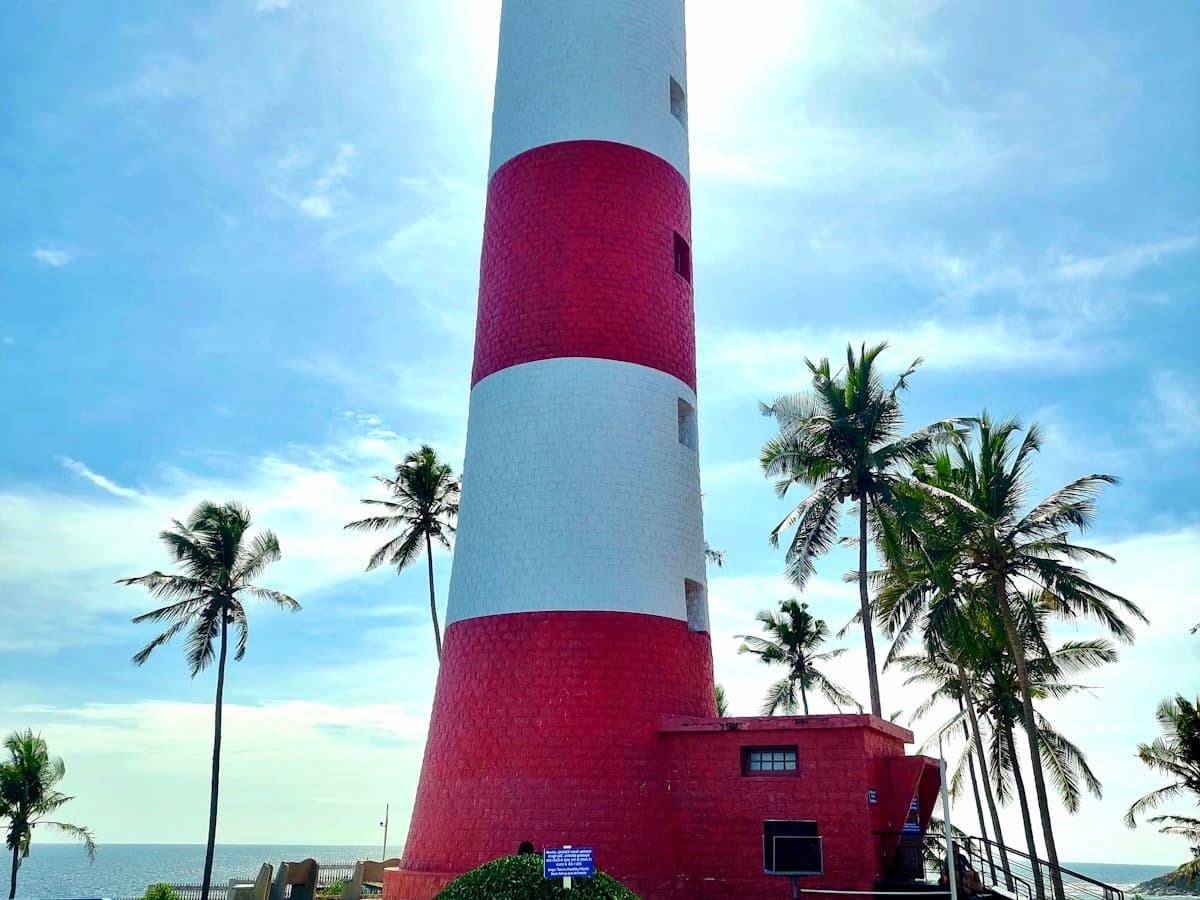 A red and white striped lighthouse tower rising above the coast at Kovalam