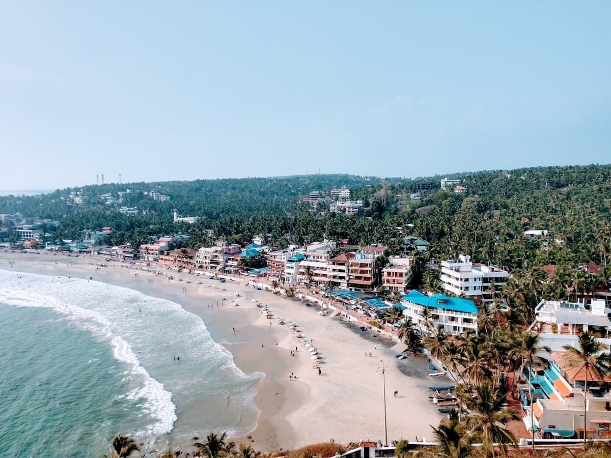 An aerial view of a curving beach and the town behind it on the Kerala coast
