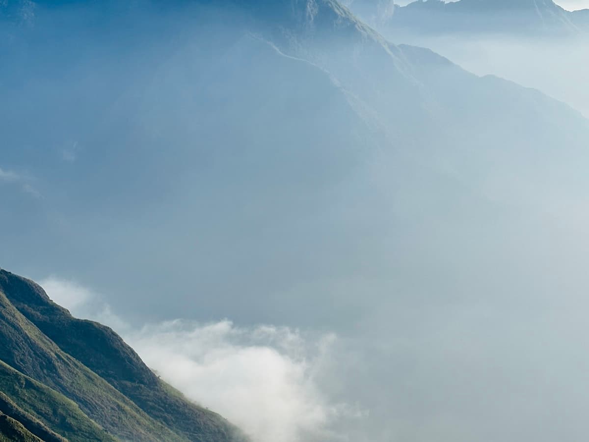 A high mountain range half covered in drifting fog above the tea hills