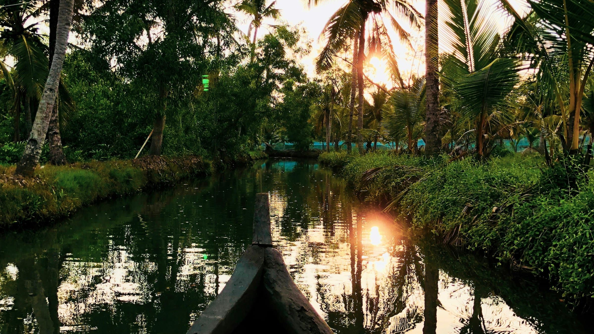 A wooden boat on a Kerala backwater lake at sunset