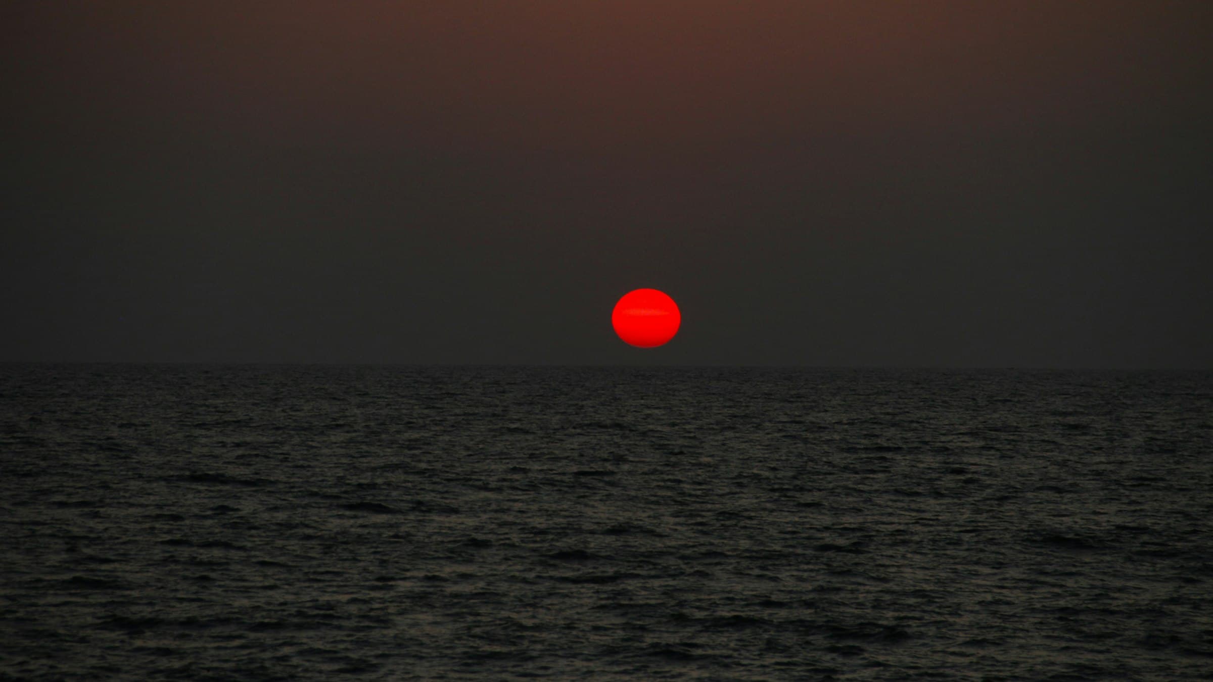 The sun setting over the Arabian Sea under a cloudy sky