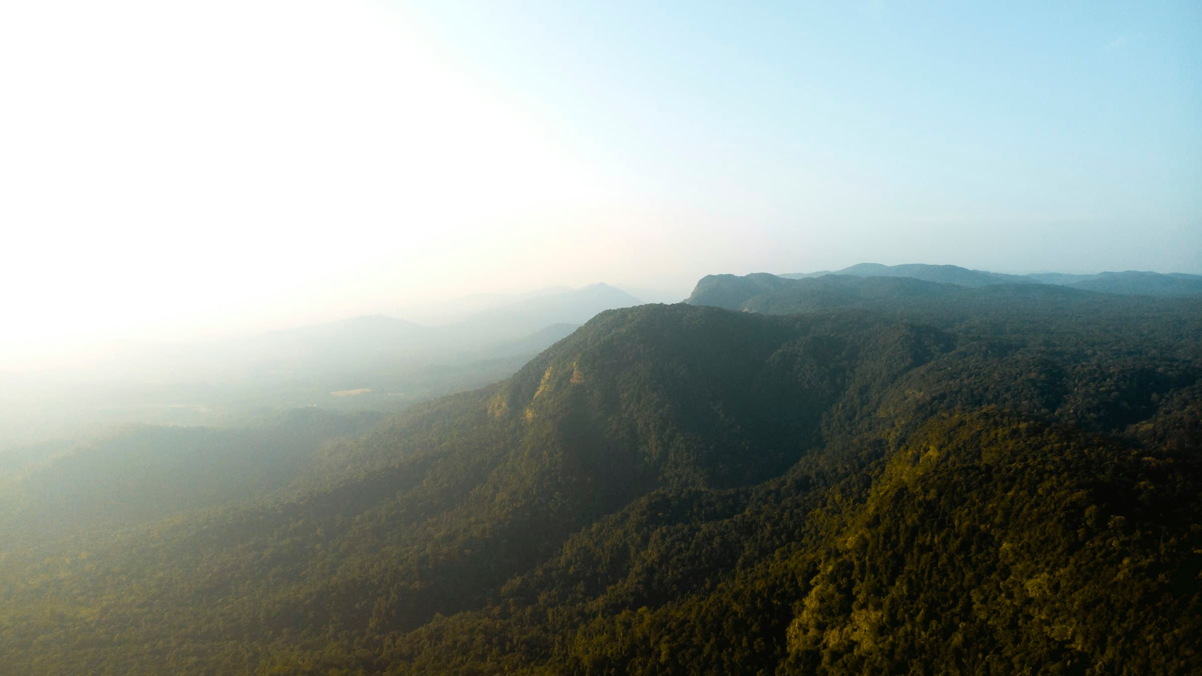 Green and brown mountain ridges under a clear blue sky in the Western Ghats