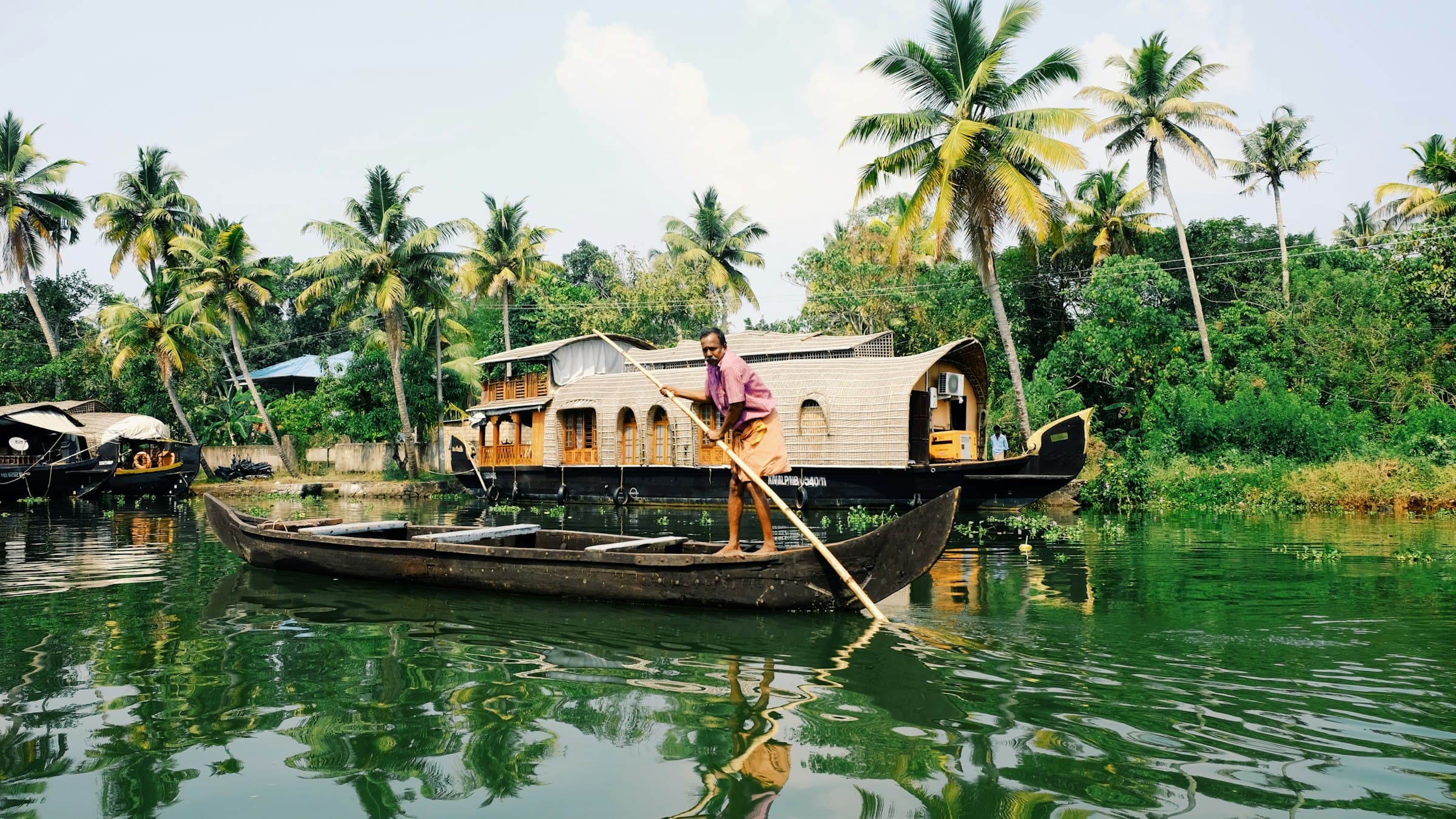 A man rowing a small boat across calm backwater in daylight
