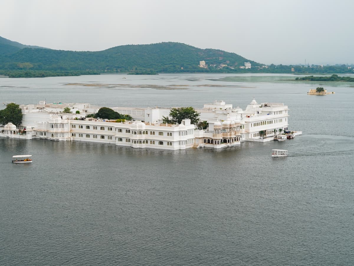 A large white building sitting above a lake