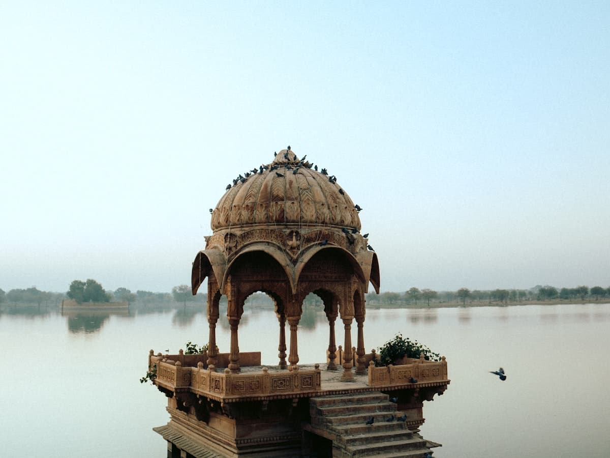 A stone gazebo sitting above a body of water