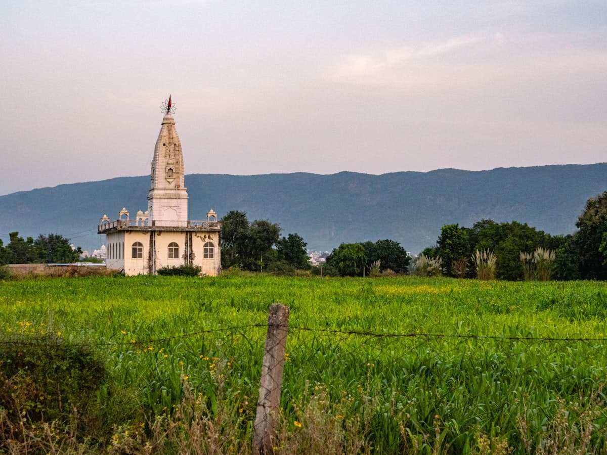 White temple building in a green field with hills behind