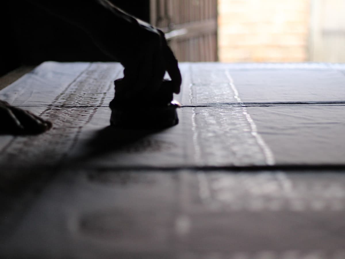 Someone stamping a pattern onto fabric