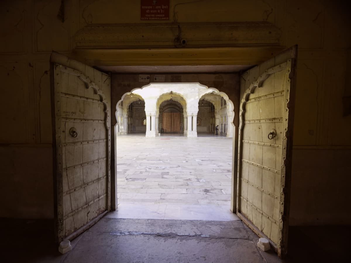 Open doors revealing an old courtyard with several arched entrances