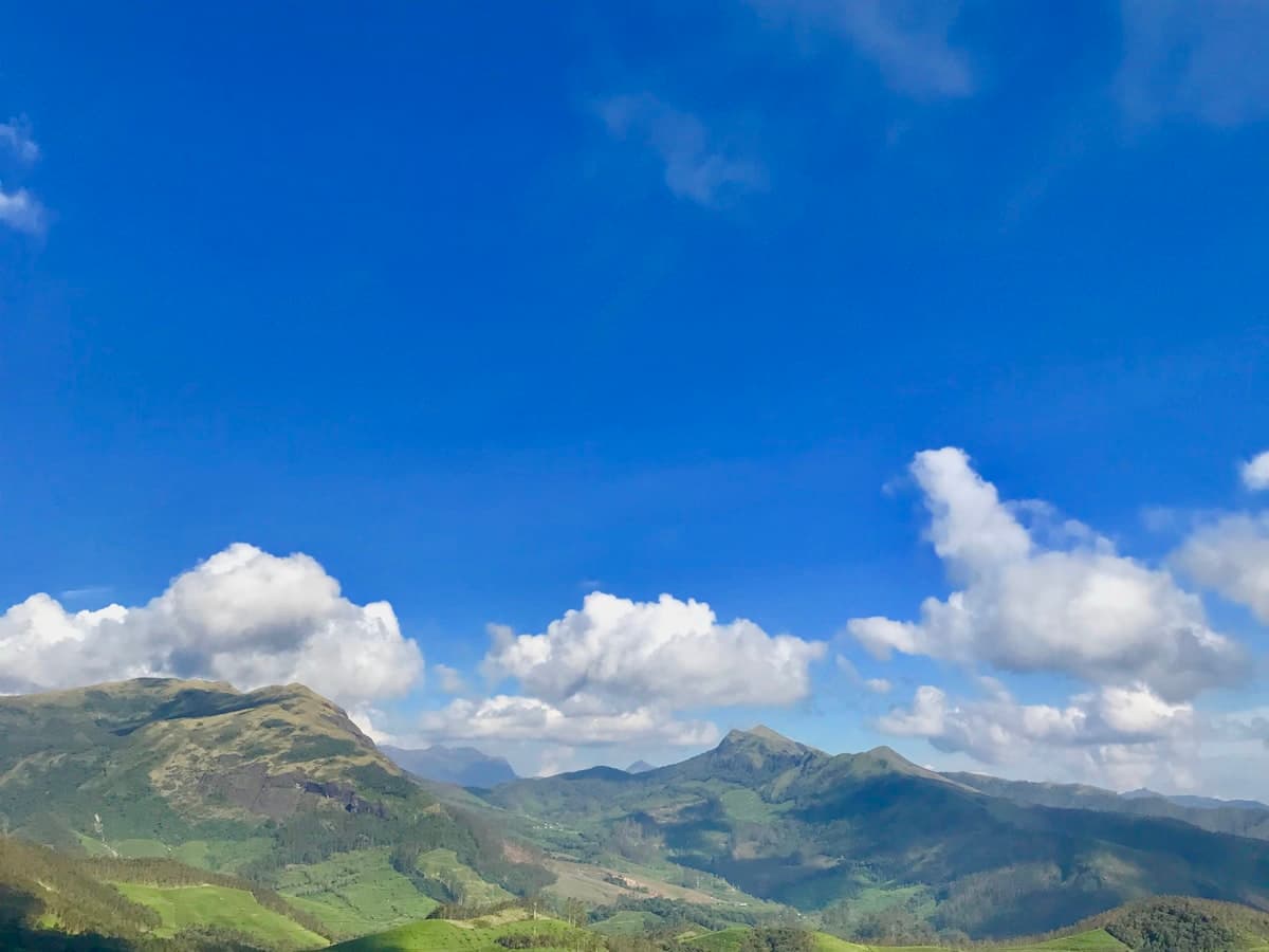 Green mountains under a blue sky with white clouds