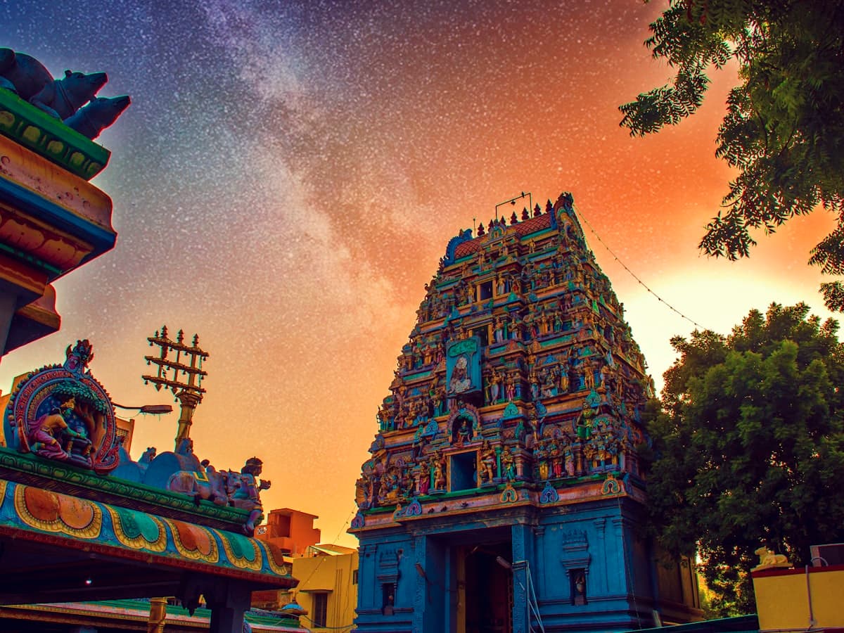 A colourful Hindu temple tower lit orange against a night sky
