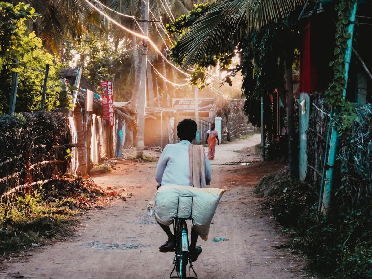 A man on a bicycle riding down a sunny village path