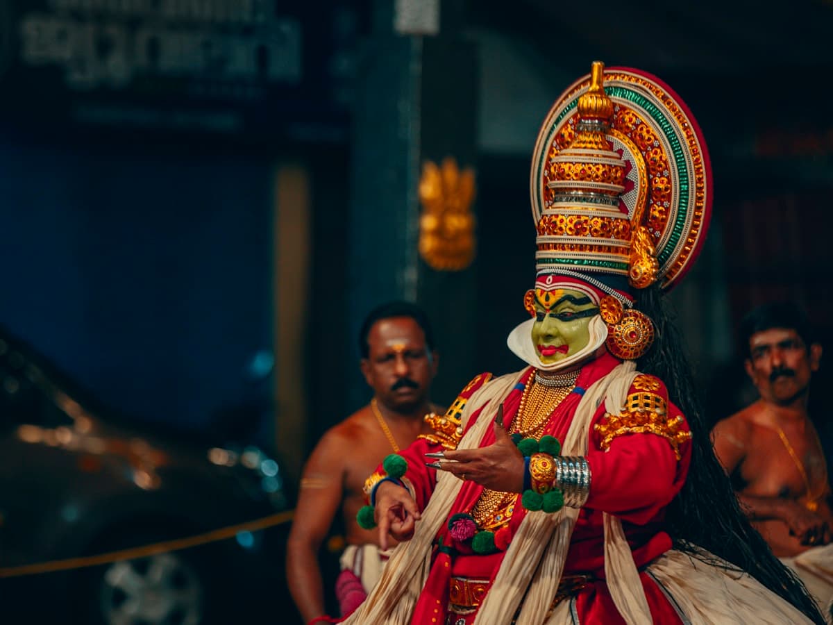 A performer in a colourful costume standing with other performers