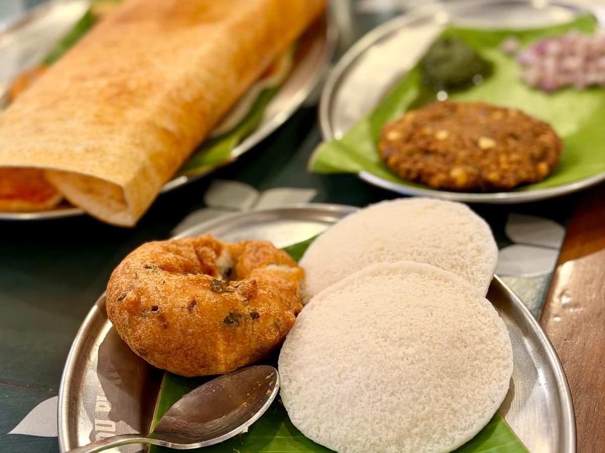 A plate of idli, vada and chutney served on a banana leaf